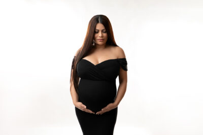 A pregnant woman in a black dress posing for a photo.
