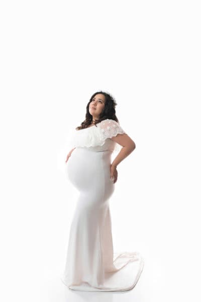 A pregnant woman in a white dress posing for a photo.