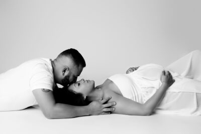 A black and white photo of a couple laying on their stomachs.