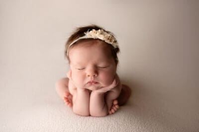 A newborn girl is laying down on a white background.
