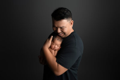 A man is holding a newborn baby in his arms.