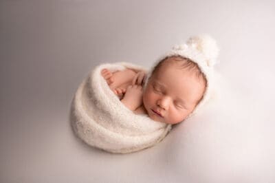 A newborn baby wrapped in a white blanket.