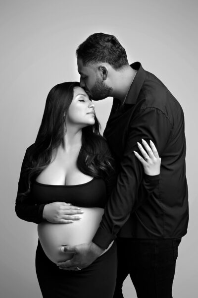 A black and white photo of a pregnant couple.
