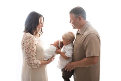 A family is holding a newborn in front of a white background.