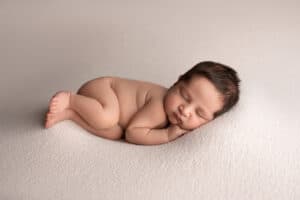 A newborn baby boy sleeping on a white background.