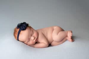 A newborn baby girl sleeping on a blue background.