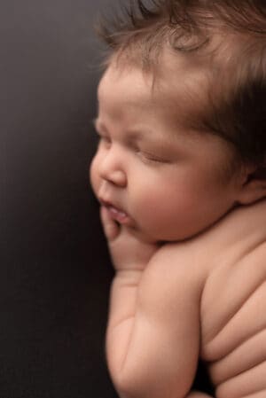 A newborn baby sleeping on a black background.