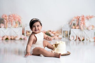 A baby girl sitting in front of a cake.