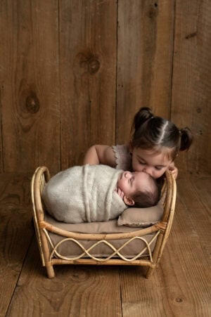 A baby and a toddler in a wicker basket.