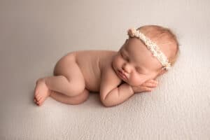 A newborn baby girl sleeping on a white background.