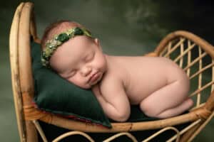 A baby girl is sleeping in a wicker basket.