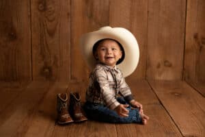 A baby wearing a cowboy hat and cowboy boots.
