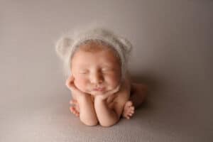 A newborn baby wearing a teddy bear hat.