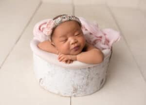 A baby girl is sleeping in a wooden box.
