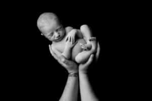 A black and white photo of a baby in someone's hands.