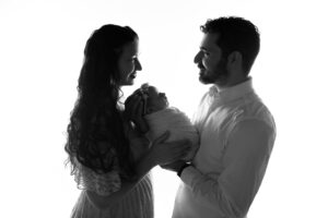 A black and white photo of a man and woman holding a baby.