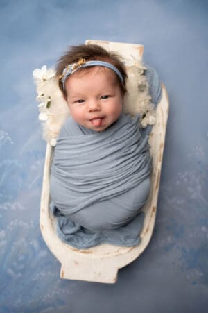 A baby girl in a blue wrap posing for a photo.