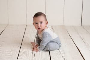 A baby sitting on a wooden floor.
