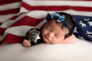 A baby girl laying on an american flag.
