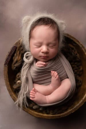 A newborn baby sleeping in a bowl.