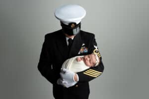 A man in a navy uniform holding a baby.