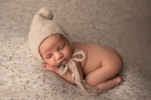 A newborn baby sleeping in a knitted hat.