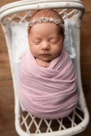 A newborn baby sleeping in a pink wrap.