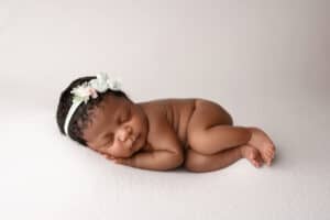 A newborn baby girl is laying on a white background.