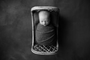 A black and white photo of a baby in a basket.