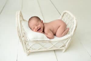 A newborn baby sleeping in a wicker basket.