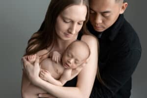 A man and woman are holding a baby in their arms.