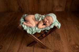 A newborn sleeping on a wooden chair.
