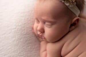 A baby sleeping on a blanket with a headband.
