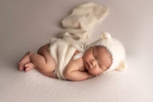 A newborn baby sleeping in a knitted hat.