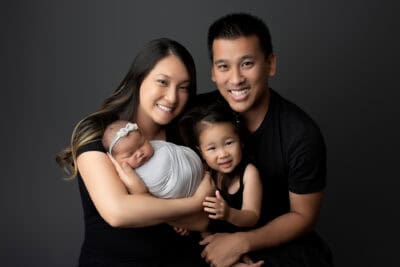 A family posing for a photo in front of a black background.