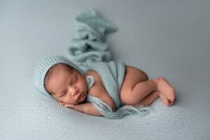 A newborn baby sleeping on a blue blanket.