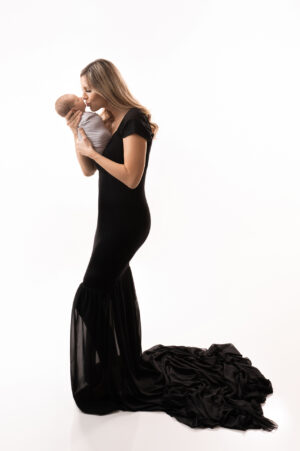 A woman in a black dress holding a baby in her arms.