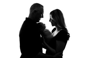 A silhouette of a man and woman holding a baby.