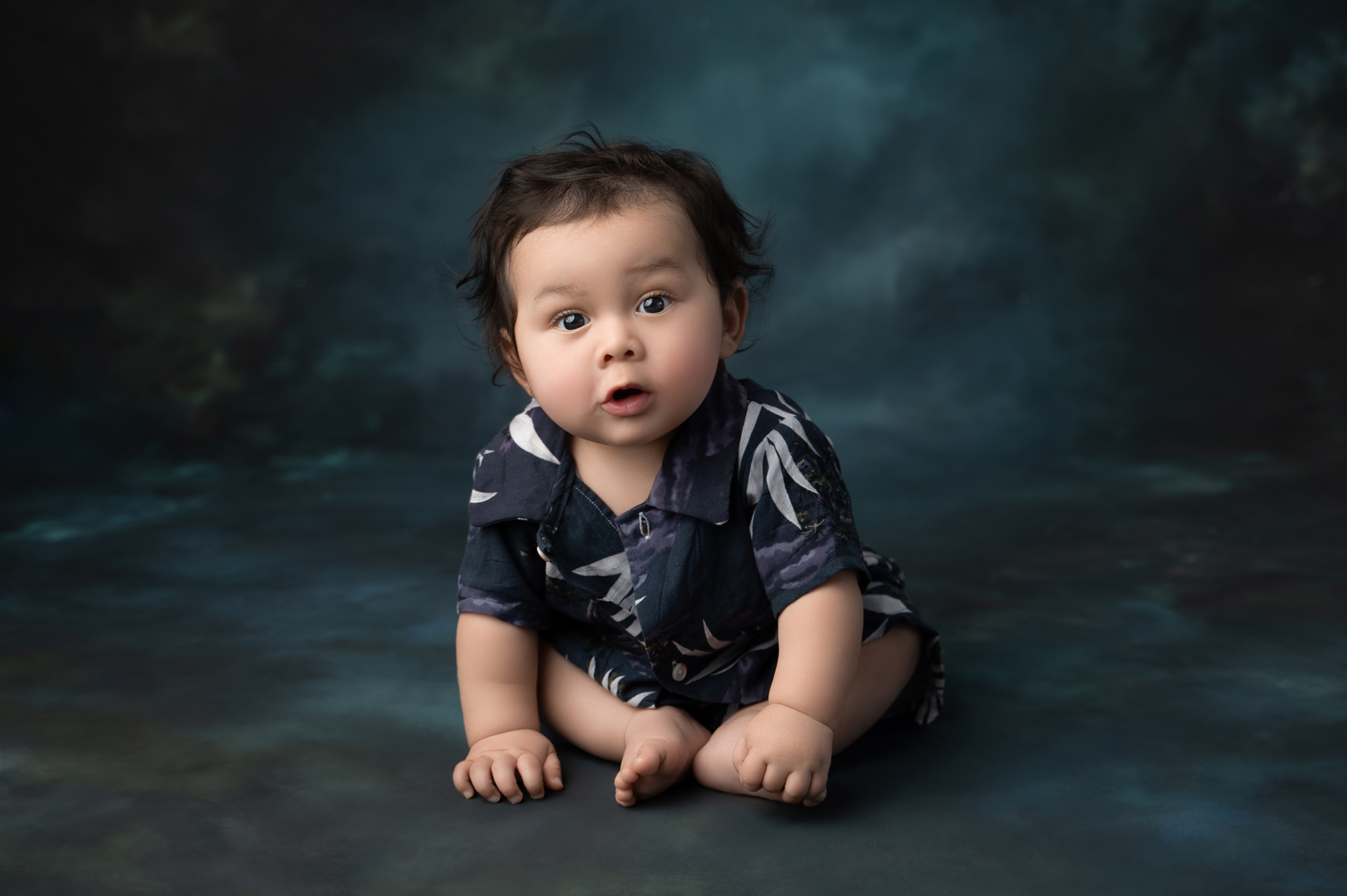 Adorable baby sitting on dark background
