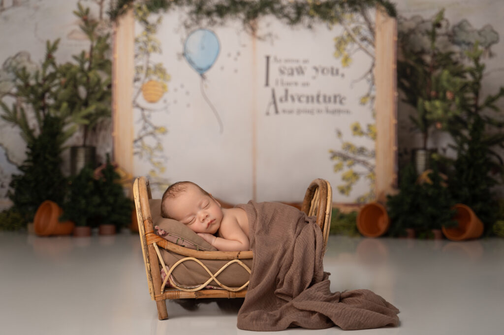 Sleeping baby in rustic bed with forest backdrop.