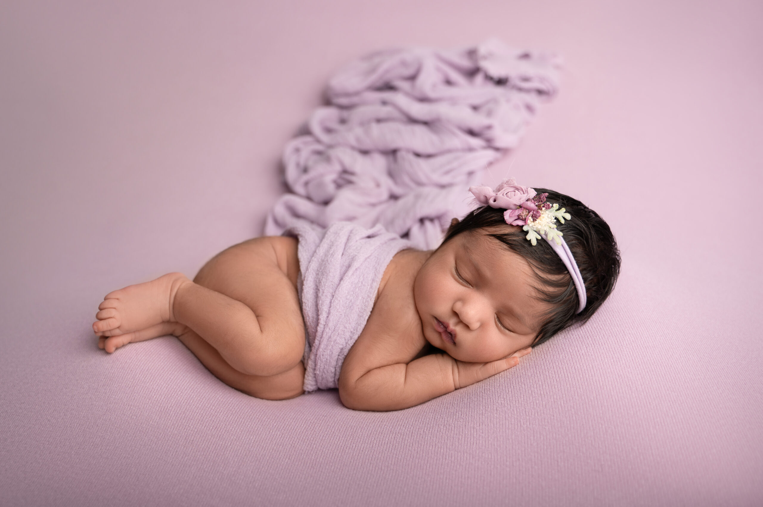 Sleeping baby swaddled in lavender blanket.