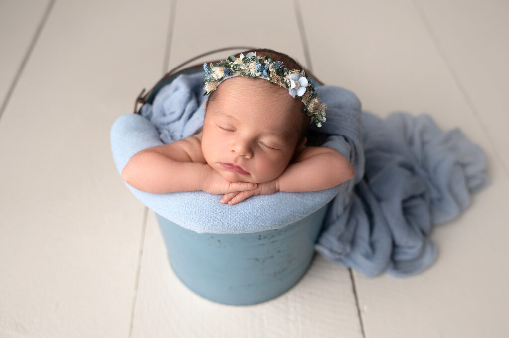 Sleeping baby in bucket with blue blanket.