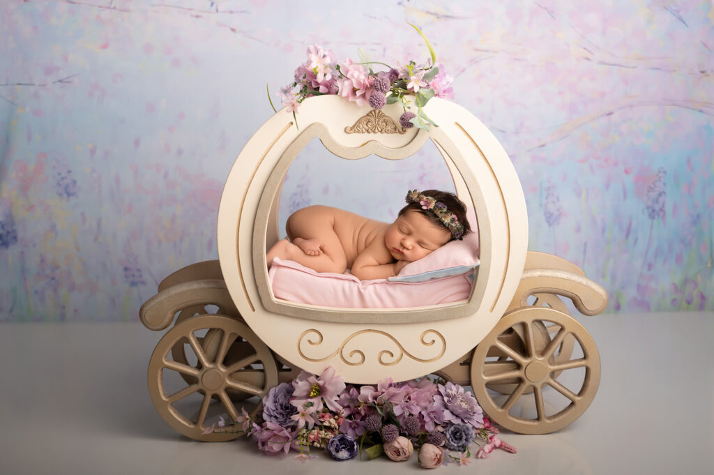 Baby sleeping in decorative floral carriage prop
