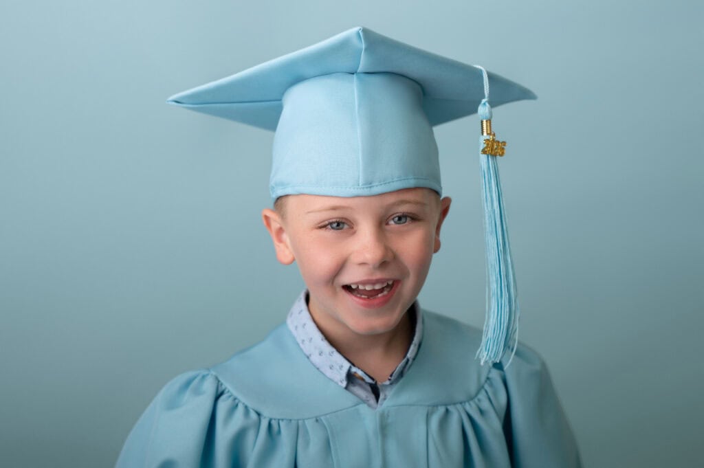 Smiling child in blue graduation cap and gown