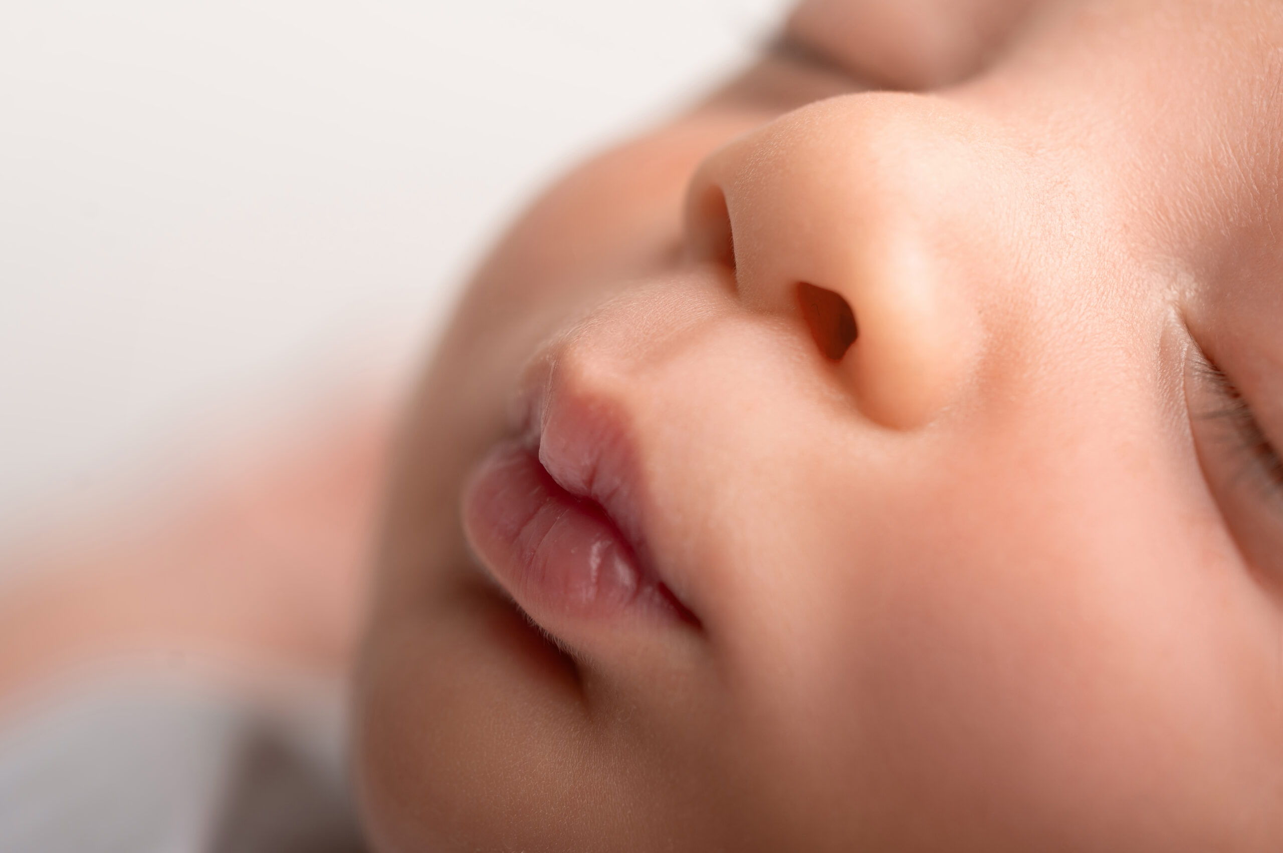 close up of a sleeping baby’s face, focusing on the nose, lips, and closed eye, with soft lighting and smooth skin visible—capturing the gentle details that a sacramento maternity and newborn photographer cherishes during a newborn photoshoot in sacramento.